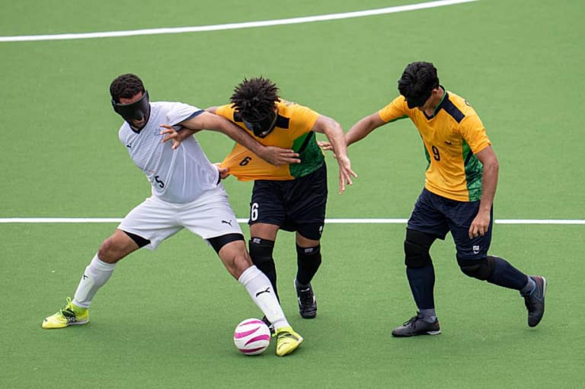 three blind footballers fight for the ball